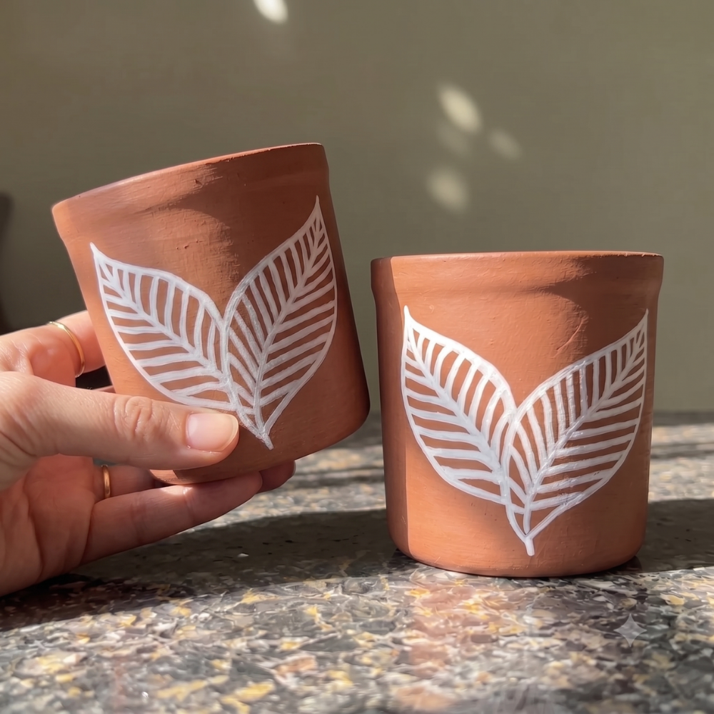  Handpainted terracotta planter placed near a bright window, showcasing a handmade pot, indoor planter, small planter, and small pot for plant lovers.